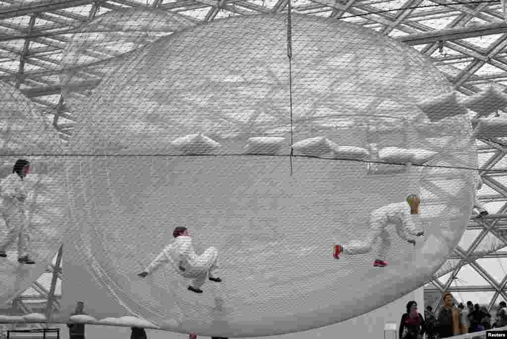 Visitors climb through the art installation &#39;In Orbit&#39; by Tomas Saraceno of Argentina at the Kunstsammlung K21 museum in Düsseldorf, Germany, June 30, 2013. The steel wire construction spans the museum&#39;s vast glass cupola on three different levels more than 25 meters above the ground. Visitors have access to the artwork and can move freely between the spheres on all three levels.