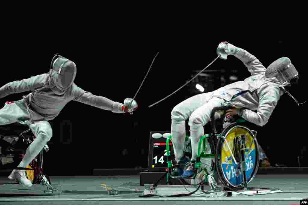 Atlet anggar Li Hao dari China (kiri) bertarung melawan Artem Manko dari Ukraina selama pertandingan anggar kursi roda pada Olimpiade Paralimpik (Paralimpiade) Tokyo 2020 di Makuhari Messe Hall di Chiba, Jepang. (Foto: AFP)