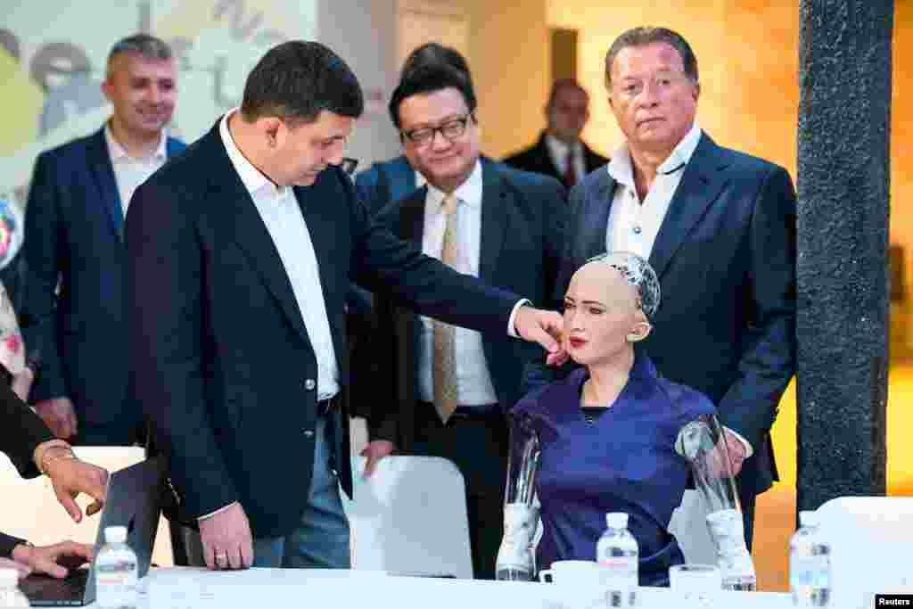 Ukrainian Prime Minister Volodymyr Groysman touches social humanoid robot Sophia, a latest creation by Hanson Robotics company, during a meeting with young inventors and officials in Kyiv.