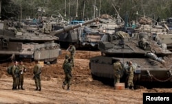 Israeli soldiers stand next to tanks and armoured personnel carriers (APC) near the border with Gaza, in southern Israel, March 26, 2019.