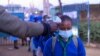 Les élèves de l'école primaire olympique font la queue pour faire mesurer leurs températures à l'entrée de l'école tôt le matin de la journée officielle de réouverture des écoles publiques le 4 janvier 2021, dans le bidonville de Kibera, au Kenya.