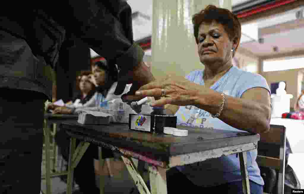 Un miembro de mesa sumerge en la tinta el dedo de un soldado luego que vot&oacute;, el domingo 14 de abril en Venezuela. 