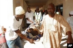 FILE - Rescue workers transport a victim of a suicide bomb attack at a refugee for treatment at a hospital in Maiduguri, Nigeria, Feb. 10, 2016. Two female suicide bombers blew themselves up in a northeast Nigerian refugee camp, killing dozens of people.