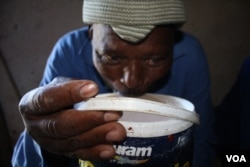 Nqileni village chief, Mabhokomela Bonakele, drinks from a bucket of sorghum beer (D.Taylor/VOA)