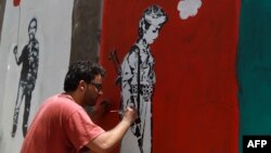 A Yemeni artist works on a mural as part of a campaign to end the recruitment of child soldiers by tribal militias in the capital Sana'a, April 10, 2014. 