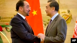 FILE - Afghan Foreign Minister Salahuddin Rabbani, left, and Chinese Foreign Minister Wang Yi, right, shake hands at the end of a joint press conference at the Ministry of Foreign Affairs in Beijing, Jan. 26, 2016.