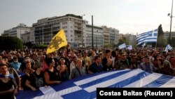 Demonstran memegang bendera Yunani selama protes terhadap kebijakan vaksinasi COVID-19 di luar gedung parlemen, di Athena, Yunani, 21 Juli 2021. (Foto: REUTERS/Costas Baltas)