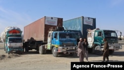 FILE - Drivers stand in front of their trucks loaded with relief materials for Afghans before crossing through the Chaman border on Dec. 17, 2021. 