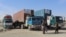 FILE - Drivers stand in front of their trucks loaded with relief materials for Afghans before crossing through the Chaman border on Dec. 17, 2021. 