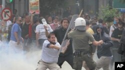 Greek protester uses a baton to hit a riot police officer during clashes in Athens' main Syntagma square, June 15, 2011