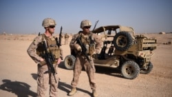 资料照片：两名美国海军陆战队员在阿富汗赫尔曼德省拉什卡尔加的一处军营观看阿富汗国民军士兵进行排除土制炸弹的演练。(2017年8月28日)