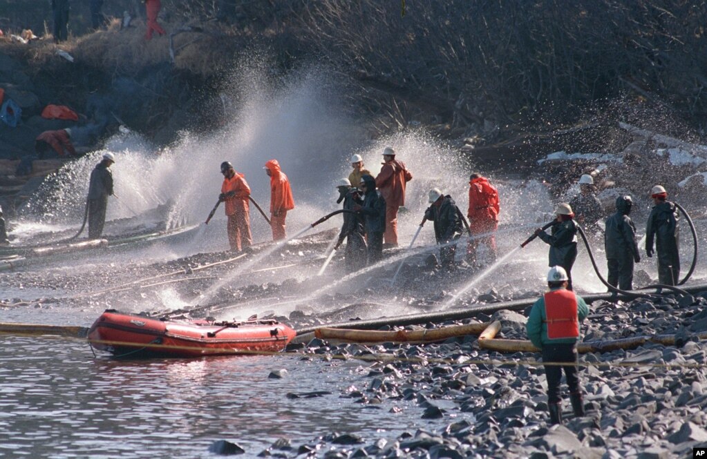 FILE - Crews use high-pressure hoses to blast the oil off rocks on this beach front on Naked Island, Alaska, April 21, 1989. This is one of two beaches that are being worked on, out of 58 beaches in the Prince William Sound.