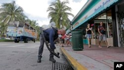  FILE - Miami-Dade mosquito-control inspector Yasser "Jazz" Compagines sprays a chemical mist into a storm drain, Aug. 23, 2016, in Miami Beach, Fla. The spread of the Zika virus has been limited in Florida thanks to aggressive mosquito control.