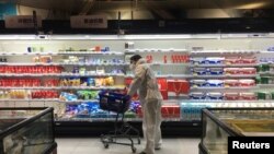 China está tratando de reanudar las actividades en todo el país en medio de la epidemia de coronavirus, pero el público sigue temeroso. Este cliente hace compras en un mercado de Wuhan completamente protegido y con máscara el 11 de febrero de 2020.
