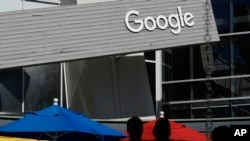 Orang-orang berjalan di depan kampus Google yang terletak di Mountain View, California, pada 24 September 2019. (Foto: AP/Jeff Chiu)