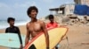 Attiq Ur Rehman, 21, walks with his teammates along the beach as they prepare to surf at Turtle Beach in Karachi, Pakistan, Sept. 4, 2024. 