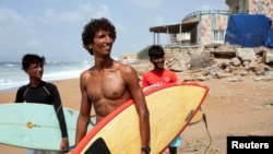 Attiq Ur Rehman, 21, walks with his teammates along the beach as they prepare to surf at Turtle Beach in Karachi, Pakistan, Sept. 4, 2024. 