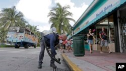 FILE - Miami-Dade mosquito control inspector Yasser "Jazz" Compagines sprays a chemical mist into a storm drain, Aug. 23, 2016, in Miami Beach, Fla. 