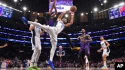 El base del Orlando Magic, Jalen Suggs, el número 4, recibe una falta del alero de Los Ángeles Lakers, Anthony Davis, en un partido de baloncesto de la NBA, el jueves 21 de noviembre de 2024, en Los Ángeles. (AP/Mark J. Terrill)