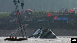 Para penyelamat di atas perahu menyaksikan kapal diderek untuk dibalikkan di Sungai Yangtze, China (5/6). (AP/Andy Wong)