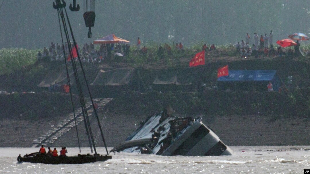 Para penyelamat di atas perahu menyaksikan kapal diderek untuk dibalikkan di Sungai Yangtze, China (5/6). (AP/Andy Wong)
