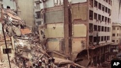 FILE - In this July 18, 1994, firefighters and rescue workers search through the rubble of the Buenos Aires Jewish Community center after a car bomb rocked the building. 