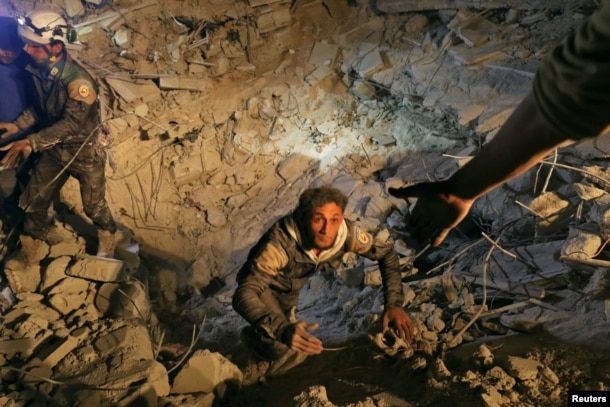 A civil defense member attempts to get out of a site hit at night by an airstrike in Saraqeb, in rebel-held Idlib province, Syria, Dec. 11, 2016.