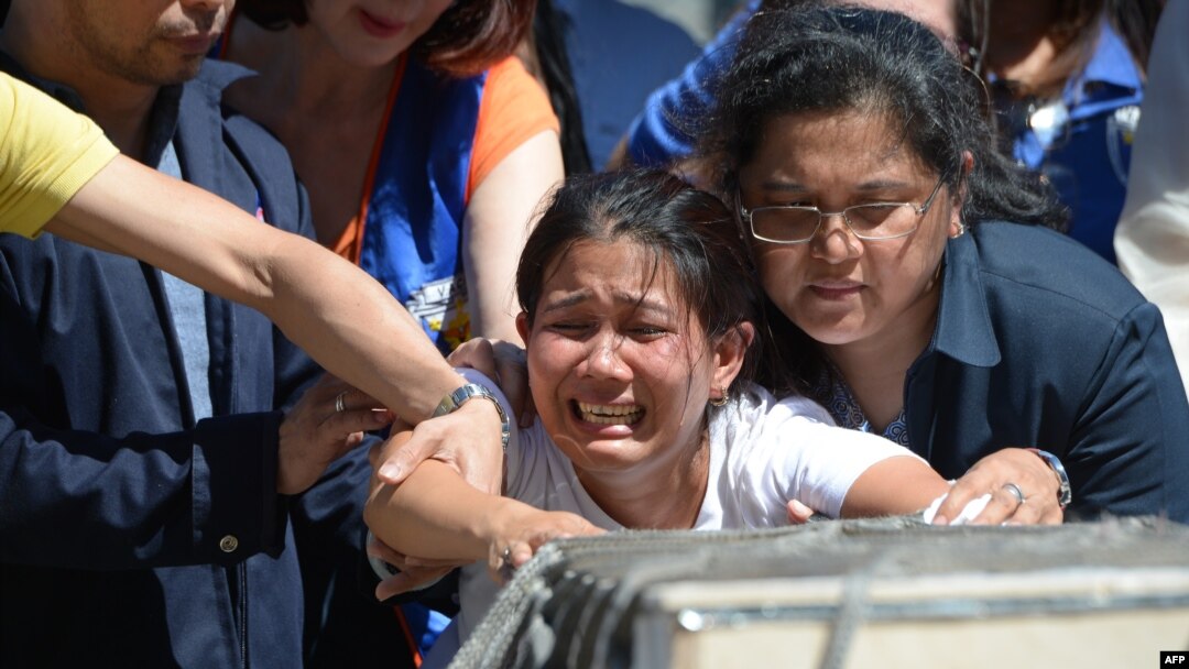Jessica (tengah), saudara perempuan TKW asal Filipina, Joanna Demafelis, yang jenazah ditemukan di dalam lemari pendingin di Kuwait, menangis di depan peti jenazah yang berisi tubuh saudaranya, tak lama setelah tiba di bandara internasional Manila, 16 Februari 2018.