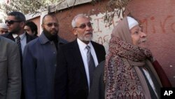 FILE - Muslim Brotherhood leader Mohammed Badie, second right, waits in line outside a polling place in Beni Suef, Egypt, to vote on a constitution drafted by Islamist supporters of President Mohammed Morsi. 