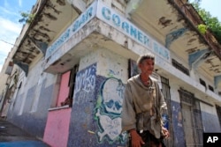 A homeless man stands in front of a closed down business in Puerta de Tierra in the outskirts of Old San Juan, Puerto Rico, Sunday, Aug. 2, 2015.