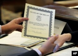 FILE - Electoral College elector William Rauwerdink shows off his ballot for president of the United States,Dec. 19, 2016, in Lansing, Mich.