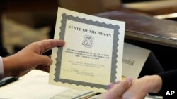 Anggota Dewan Elektoral William Rauwerdink menunjukkan kertas suaranya untuk presiden Amerika Serikat (19/12) di Lansing, Michigan. (AP/Carlos Osorio)