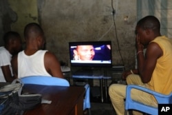 People in Kinshasa, D.R.C., look at a program reporting on the death of former heavyweight boxing champion Muhammad Ali, June 4, 2016.