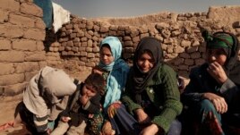 Aziz Gul, second from right, and her 10-year-old daughter Qandi, center, sit outside their home with other family members, near Herat, Afghanistan. Dec. 16, 2021. Qandi's father sold her into marriage without telling his wife, Aziz.