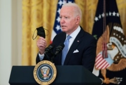 Presiden AS Joe Biden memegang maskernya saat berbicara tentang laju vaksinasi COVID-19 di Amerika Serikat, di Ruang Timur Gedung Putih di Washington, D.C., AS, 29 Juli 2021. (REUTERS/Evelyn Hockstein)