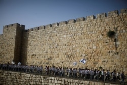 Para pemuda membawa bendera Israel selama parade menandai Hari Yerusalem di tengah ketegangan Israel-Palestina, di sepanjang tembok yang mengelilingi Kota Tua Yerusalem, 10 Mei 2021. (REUTERS/Nir Elias/File Photo)