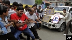 Indian people pull a car by rope and shout slogans during a protest against the price hike in diesel and capping the number of subsidized cooking gas cylinders in Ahmadabad, India, September 14, 2012.