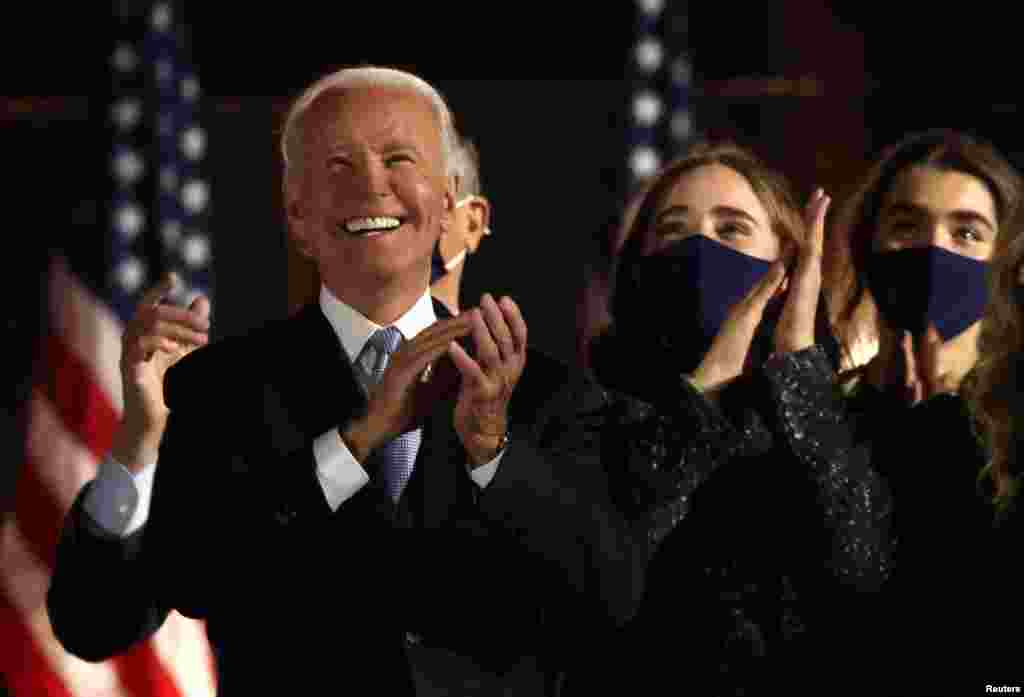 Democratic 2020 U.S. presidential nominee Joe Biden applauds next to his granddaughters after speakig during his election rally, after news media announced that he has won the 2020 presidential election.