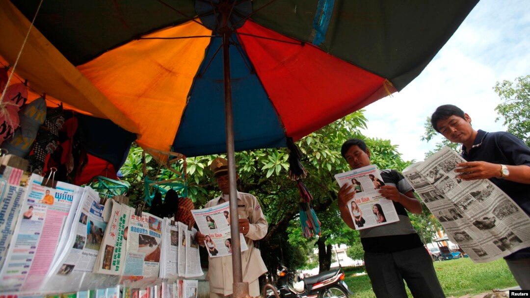 Warga Phnom Penh membaca berita-berita terkait pemilihan umum (10/8). (Reuters/Samrang Pring)
