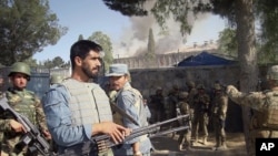 Afghan policemen, U.S. and Afghan soldiers on alert near the police traffic department building, which was under attack by insurgents in Khost, eastern of Afghanistan, May 22, 2011