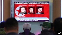 People watch a TV news report screen showing portraits of three Americans, Kim Dong Chul, left, Tony Kim and Kim Hak Song, right, detained in the North Korea at the Seoul Railway Station in Seoul, South Korea, May 3, 2018.