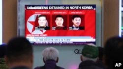 People watch a TV news report screen showing portraits of three Americans, Kim Dong Chul, left, Tony Kim and Kim Hak Song, right, detained in the North Korea at the Seoul Railway Station in Seoul, South Korea, May 3, 2018. 