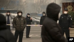 FILE - Plainclothes and uniformed police stand guard near Beijing's No. 2 People's Intermediate Court during a trial there of a human rights lawyer, in Beijing, China, Dec. 22, 2015. During the 2015 lawyer crackdown alone, China put 17 rights lawyers and activists under what is called residential surveillance.