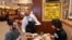 FILE - A waiter serves lunch at Junior's Restaurant in New York. NYC will soon require proof of COVID-19 vaccinations for anyone who wants to dine inside at a restaurant.