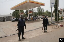 Des policiers montent la garde devant une station de carburant à Bamako (24 mars 2012)