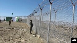 FILE - Pakistani soldiers stand guard at a newly erected fence between Pakistan and Afghanistan at Angore Adda, Pakistan, Oct. 18, 2017. 