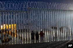 FILE - Children watch the movements of the U.S. Border Patrol agents from the Mexican side where the border meets the Pacific Ocean, Tijuana, Mexico.