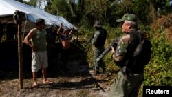 FILE - Agents of the Brazilian Institute for the Environment and Renewable Natural Resources check a man at in illegal logging camp during "Operation Green Wave," Aug. 21, 2017. Trusting that every effort will help to save rainforest, Environment Minister Jose Sarney Filho said this week that the preliminary data showed a drop from last year. "Everything indicates that the curve is falling," he said. "We're optimistic." 