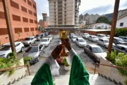 Pastor Jonathan Gonzalez memimpin Misa Minggu lantatur di halamana parkir gereja, untuk mencegah penularan virus corona di kawasan El Paraiso, Caracas, Venezuela, 25 Oktober 2020. (Foto: AP)