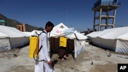 Afghan health workers in protective suits spray disinfectant on tents to help curb the spread of the coronavirus in the first quarantine camp for Afghan refugees crossing Torkham border from Pakistan to Afghanistan, April 4, 2020.